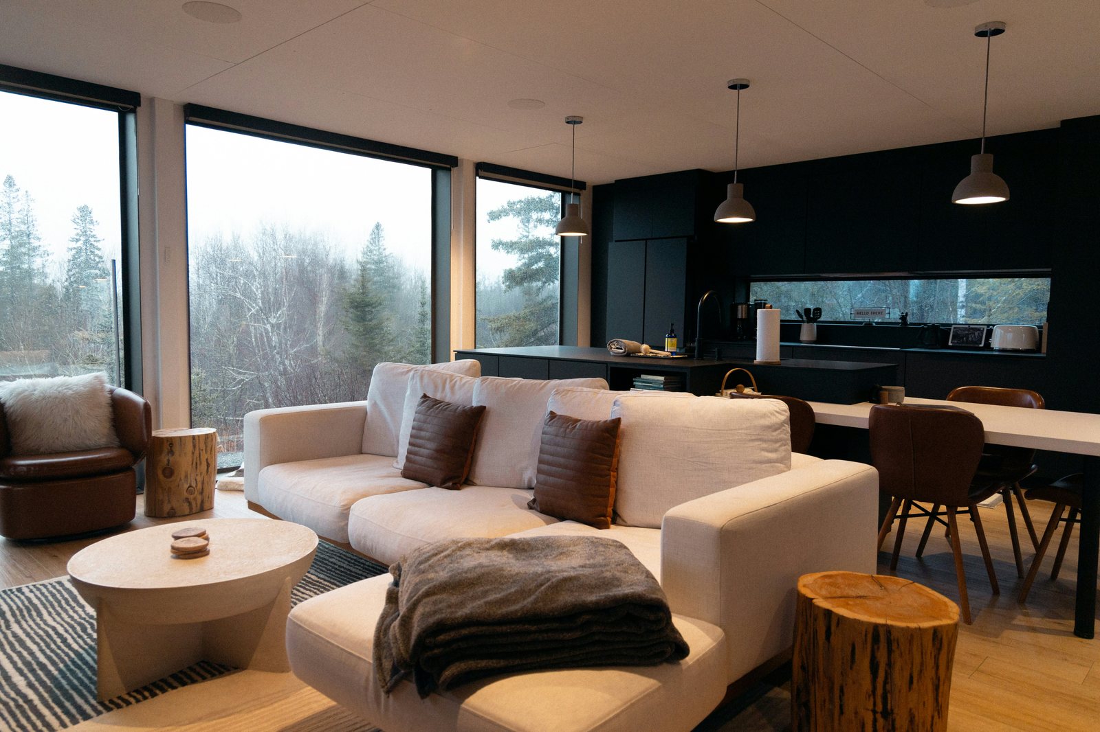 A living room with tall windows onto pines