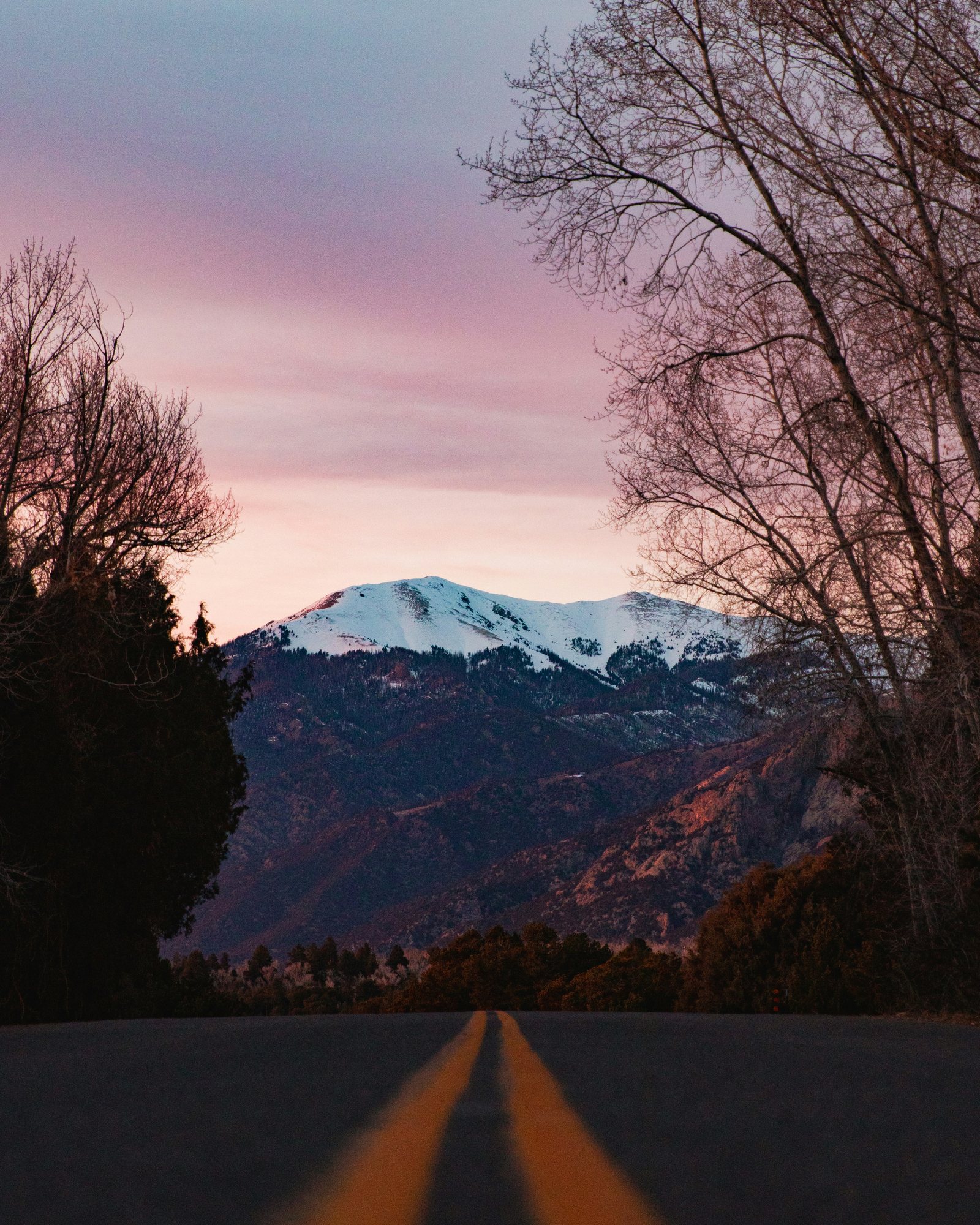 A road toward a snow-capped peak at sunset